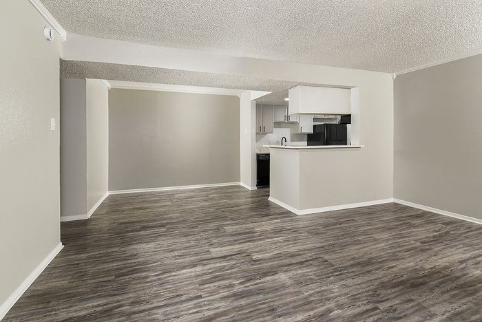 Modern open-plan living area featuring sleek hardwood flooring and a stylish kitchen with contemporary cabinetry.