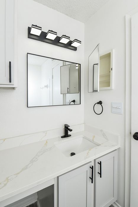 Elegant bathroom with a sleek marble countertop and modern black fixtures, offering a luxurious feel.