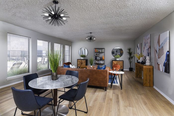 Inviting modern living room with elegant decor, featuring a chic round dining table, stylish lighting fixtures, and large windows providing abundant natural light.