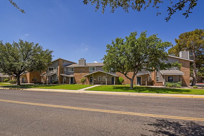 Charming suburban apartment complex surrounded by lush greenery and mature trees, perfect for family living.
