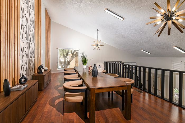 Elegant dining area with stylish wooden accents, featuring a modern table, designer chairs, and chic pendant lighting.