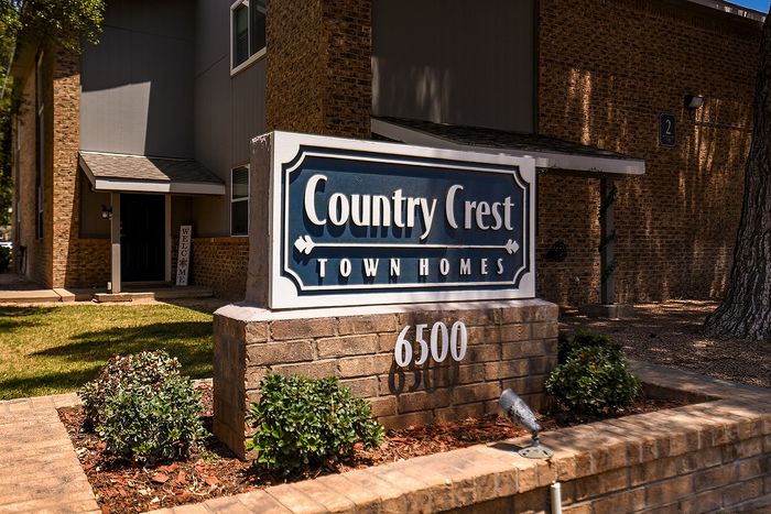 Welcoming entrance to Country Crest Town Homes with elegant sign and lush landscaping.