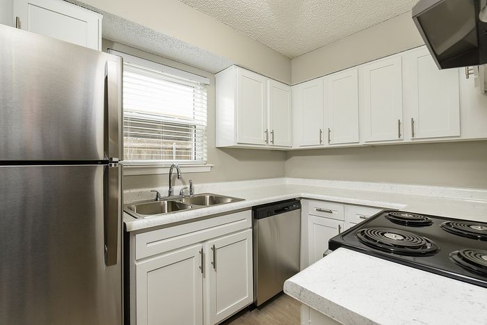 Modern kitchen featuring sleek stainless steel appliances, pristine white cabinets, and elegant countertops.