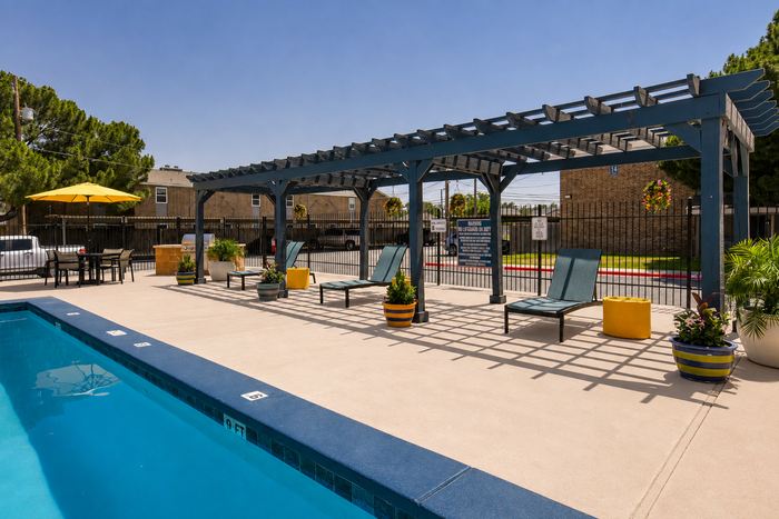 Inviting outdoor pool area with comfortable lounge chairs and shaded pergola, perfect for relaxing on a sunny day.