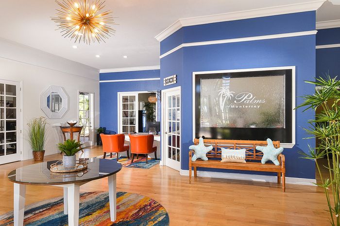 Inviting apartment lobby with vibrant blue walls, modern decor, and welcoming seating area featuring a stylish chandelier.