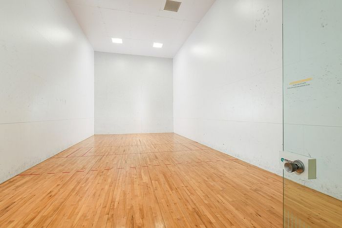 Spacious indoor squash court with polished wooden floors, perfect for recreation and fitness enthusiasts.