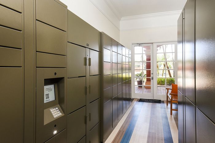 Modern apartment package room featuring sleek secure lockers with accessible entry and natural light from large patio doors.