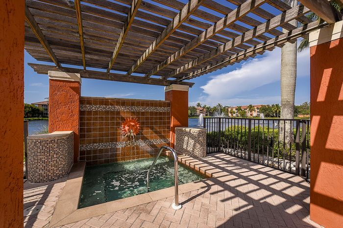 Charming patio space with a decorative water feature overlooking a serene lakeside view, perfect for relaxation.
