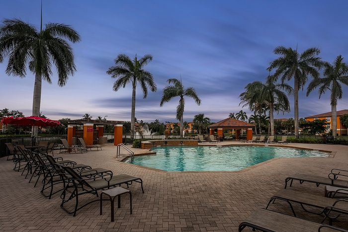 Luxurious outdoor pool area surrounded by palm trees and lounge chairs, perfect for relaxation and enjoying the tranquil atmosphere.