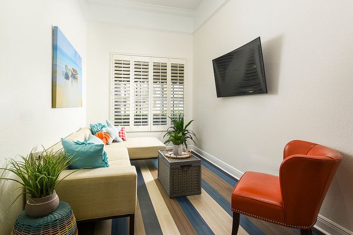 Bright and modern living room with elegant decor, featuring a cozy beige sectional, vibrant cushions, and a sleek mounted TV.