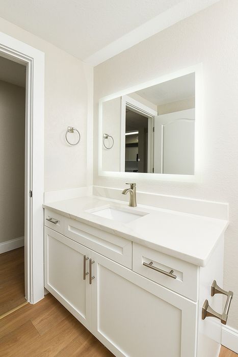 Elegant bathroom with a modern white vanity and sleek built-in sink, complemented by a large illuminated mirror.