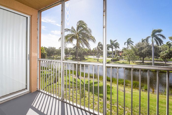 Sunny enclosed balcony with serene water views and lush palm trees in the backdrop - perfect for relaxation.