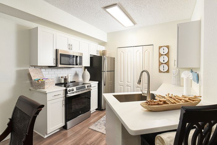 Elegant modern kitchen with stainless steel appliances, white cabinetry, and a cozy breakfast bar.