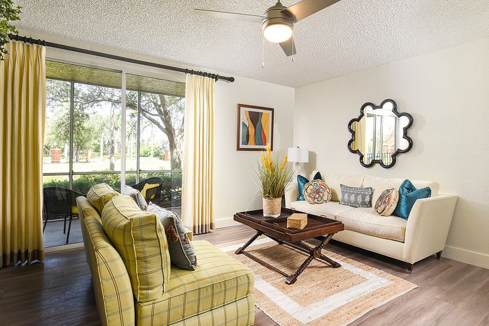Charming living room with cozy seating, vibrant pillows, and a large window offering serene garden views.