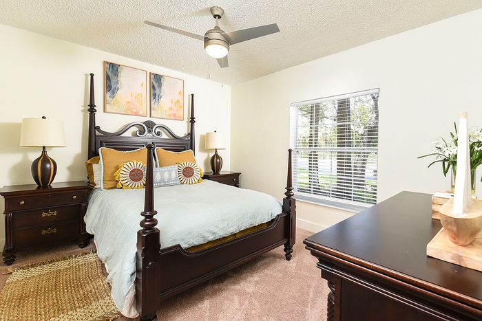 Inviting bedroom with elegant four-poster bed, soft lighting, and large window offering natural light.