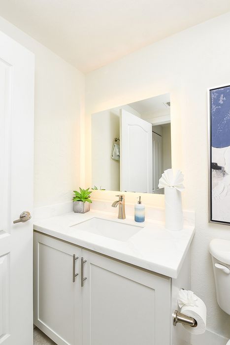 Bright and modern bathroom with elegant white vanity, illuminated mirror, and contemporary fixtures.