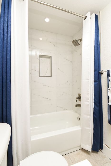 Elegant bathroom featuring a modern bathtub with stylish white and blue shower curtains, complemented by sleek chrome fixtures.