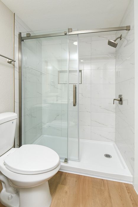Modern bathroom featuring a sleek glass shower enclosure, polished chrome fixtures, and elegant white marble tiles.