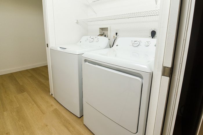Modern laundry room with sleek washer and dryer units on elegant hardwood flooring.