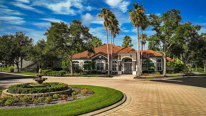 Charming residential property surrounded by lush greenery, featuring a beautifully maintained garden and elegant architecture with red-tiled roofing.