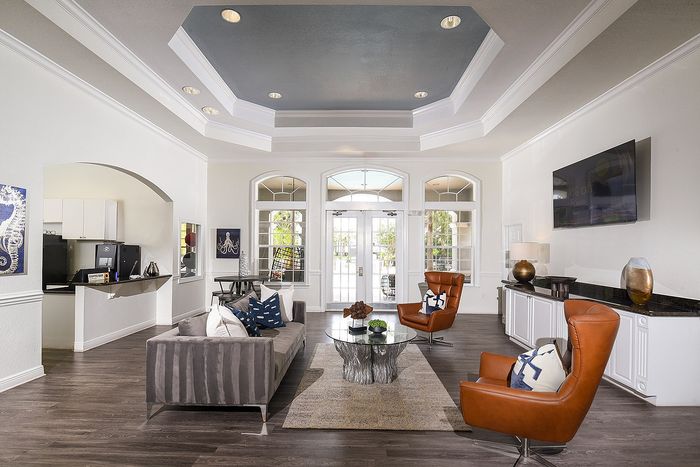 Elegant modern living room with high ceilings, featuring chic furniture and natural light streaming through large windows.