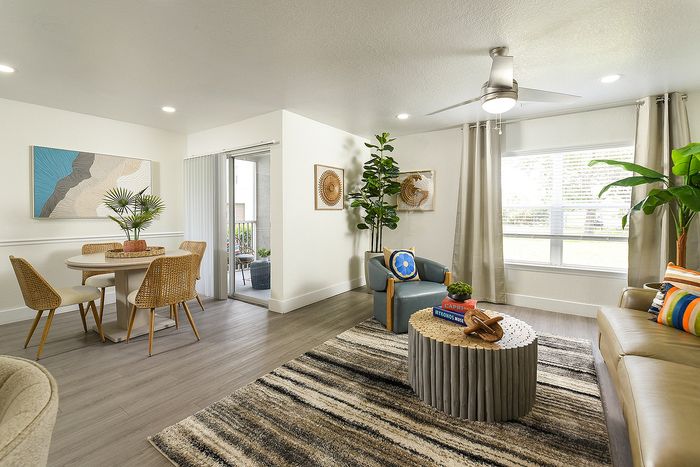 Modern living room with bright decor, cozy seating, and large windows offering ample natural light.