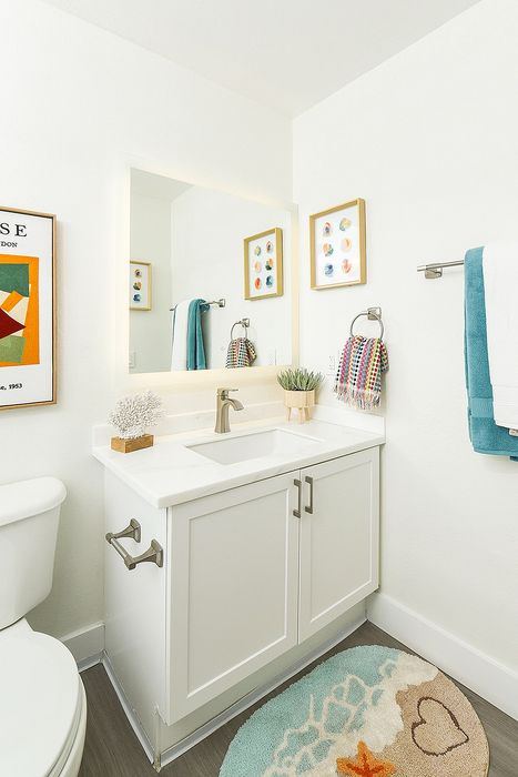 Bright and modern bathroom with a sleek white vanity, colorful decor, and vibrant wall art, exuding a charming and inviting atmosphere.
