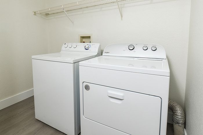 Modern laundry room featuring a sleek washer and dryer set with spacious shelving above.