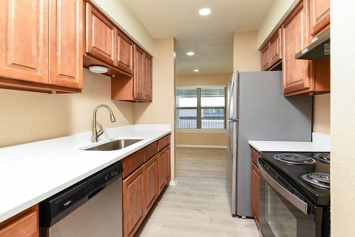 Modern kitchen with elegant wooden cabinets, stainless steel appliances, and a sleek quartz countertop.