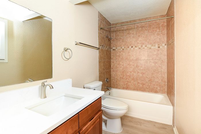 Elegant bathroom with a modern vanity, large wall mirror, and a tiled bathtub, creating a serene and stylish retreat.