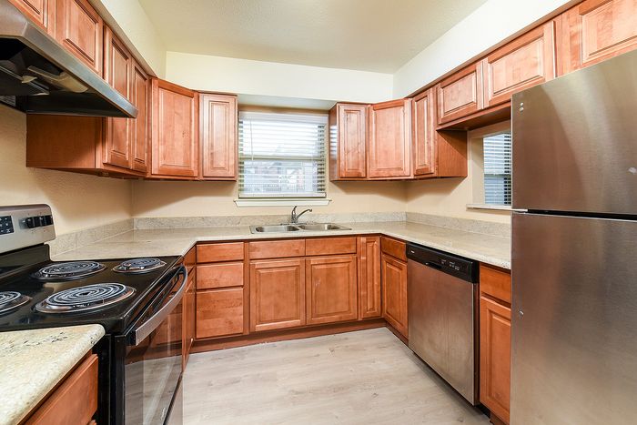 Modern kitchen with stainless steel appliances, elegant wooden cabinetry, and ambient natural light.
