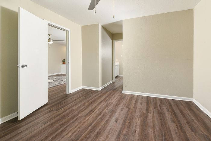 Elegant room with sleek wooden flooring, open doorways, and neutral walls offering a spacious and inviting ambiance.