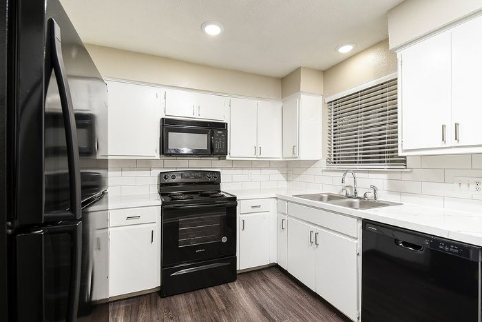 Modern kitchen with sleek black appliances, white cabinetry, and subway tile backsplash, creating a stylish and functional space.