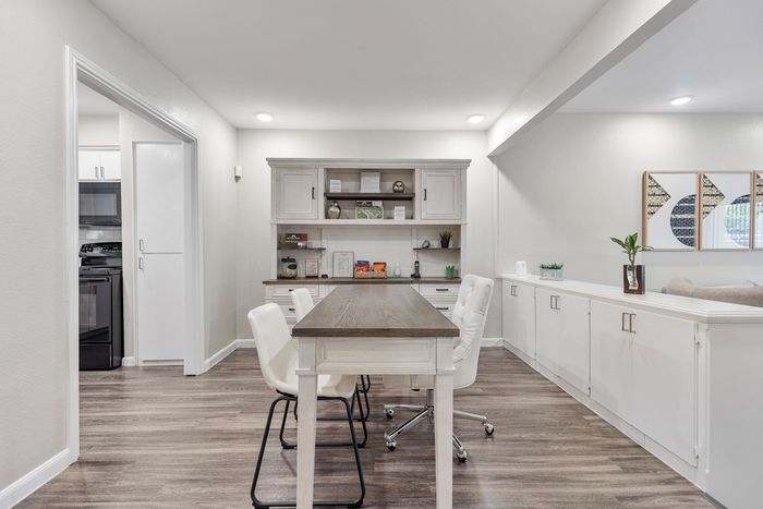 Bright and inviting office space featuring sleek white cabinets, modern decor, and a spacious wooden table with comfortable seating.