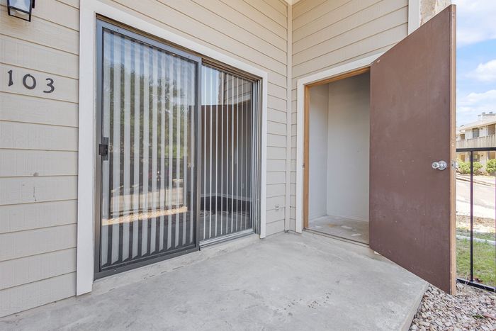 Inviting apartment entryway featuring a modern glass sliding door leading to a cozy outdoor space.