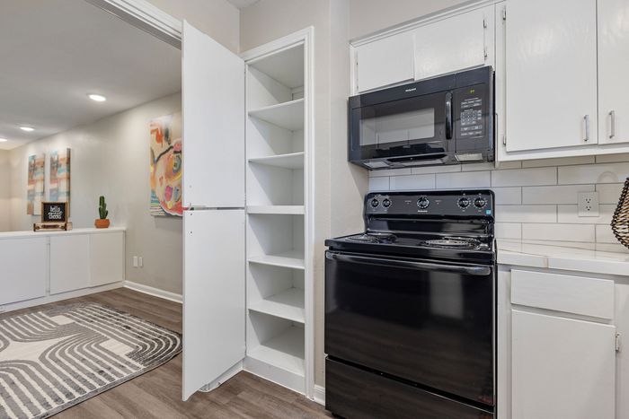 Modern kitchen with sleek black appliances, built-in shelving, and elegant artwork, offering a stylish and functional space.