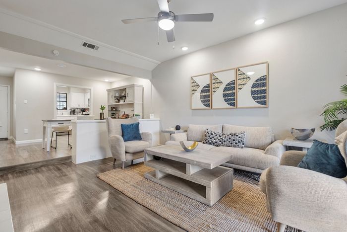 Inviting living room with stylish decor, featuring comfortable seating, modern artwork, and an open layout leading to a chic kitchen area.