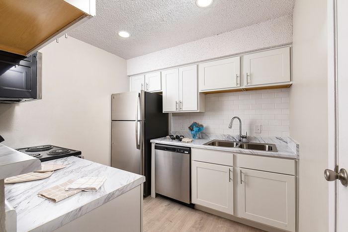 Modern kitchen with sleek white cabinets, stainless steel appliances, and elegant marble countertops.