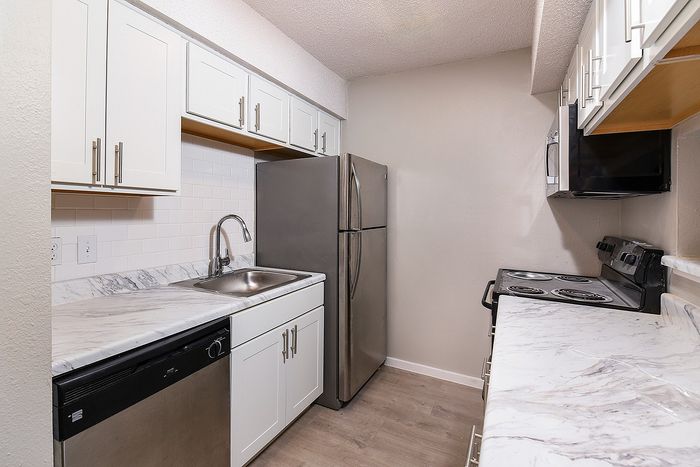 Sleek modern kitchen boasting stainless steel appliances, elegant white cabinetry, and chic marble countertops.