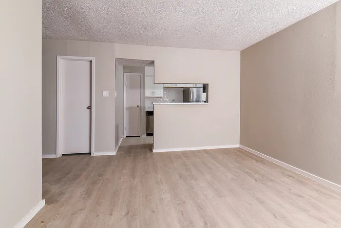 Bright and spacious living area with modern wood flooring and a stylish kitchen pass-through, perfect for entertaining.