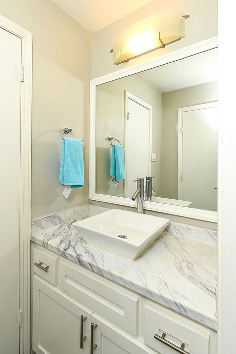 Elegant bathroom with a modern marble countertop and sleek vessel sink, accented by a soft blue towel and warm ambient lighting.