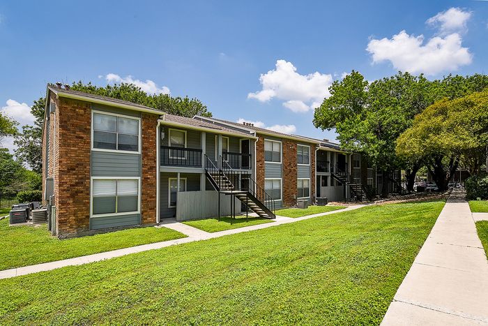 Charming multi-unit apartment complex with a modern exterior, surrounded by lush greenery and bathed in sunlight.