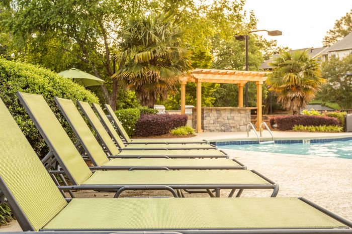 Relaxing poolside lounge area with chaise lounges at Pointe at Canyon Ridge apartments for rent in Atlanta, GA