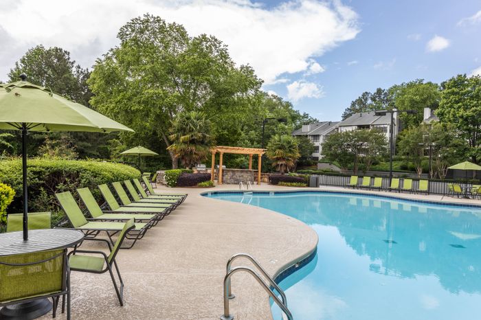 Resort-inspired swimming pool with lounge chairs and umbrellas at Pointe at Canyon Ridge apartments for rent in Atlanta, GA