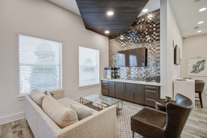 Community clubhouse lounge area with ample seating, TV, and luxurious finishes at The Adley Craig Ranch apartments for rent