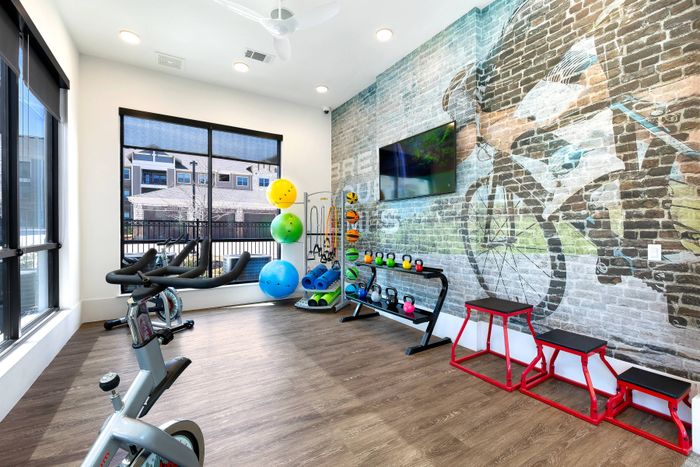 Spin room with free weights 24-hour fitness center with cardio and training equipment at The Adley Craig Ranch apartments for rent in McKinney, TX