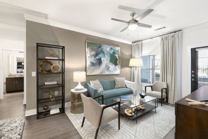 Spacious living room with ample seating, lofty 9-ft. ceilings with crown molding, and bay window at The Adley Craig Ranch apartments for rent