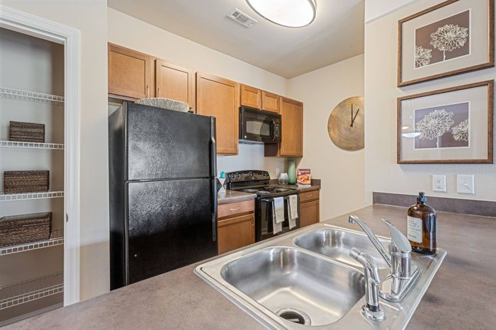 Modern and spacious kitchen with brown cabinetry and stainless steel appliances at St. James at Goose Creek apartments for rent