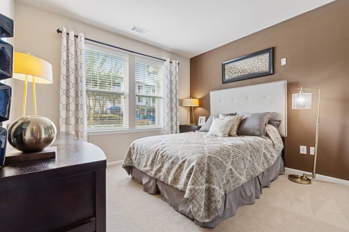 Furnished bedroom with oversized window for natural light at St. James at Goose Creek apartments for rent