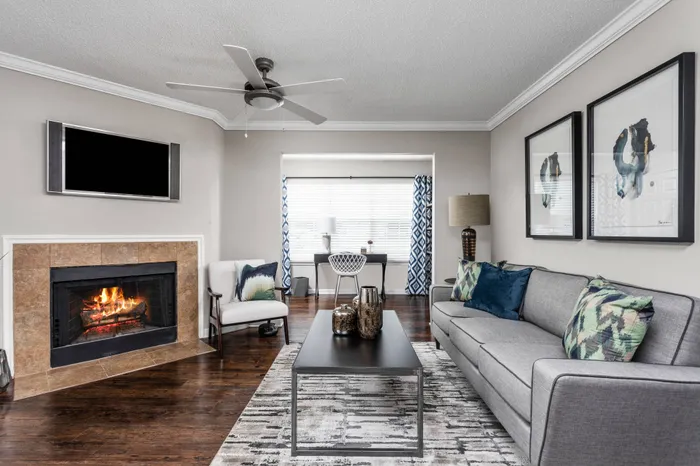 Apartment living room with fireplace, hardwood floors, and ceiling fan